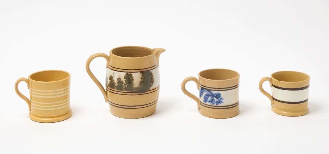 Four Yellowware Items: Four yellowware items consisting of a jug and three mugs. The jug with a white band containing dendritic (seaweed) decoration in dark green. One mug has a central band with dendritic decoration. One