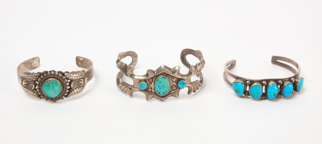 Three Navajo Silver Cuff Bracelets: Three Navajo silver and turquoise cabochon cuff bracelets. Largest is sand-cast (1.52 ozt.), single stone (1.095 ozt.), and row of 5 stones (0.97 ozt). Southwestern US, 20th century. Total Weight: