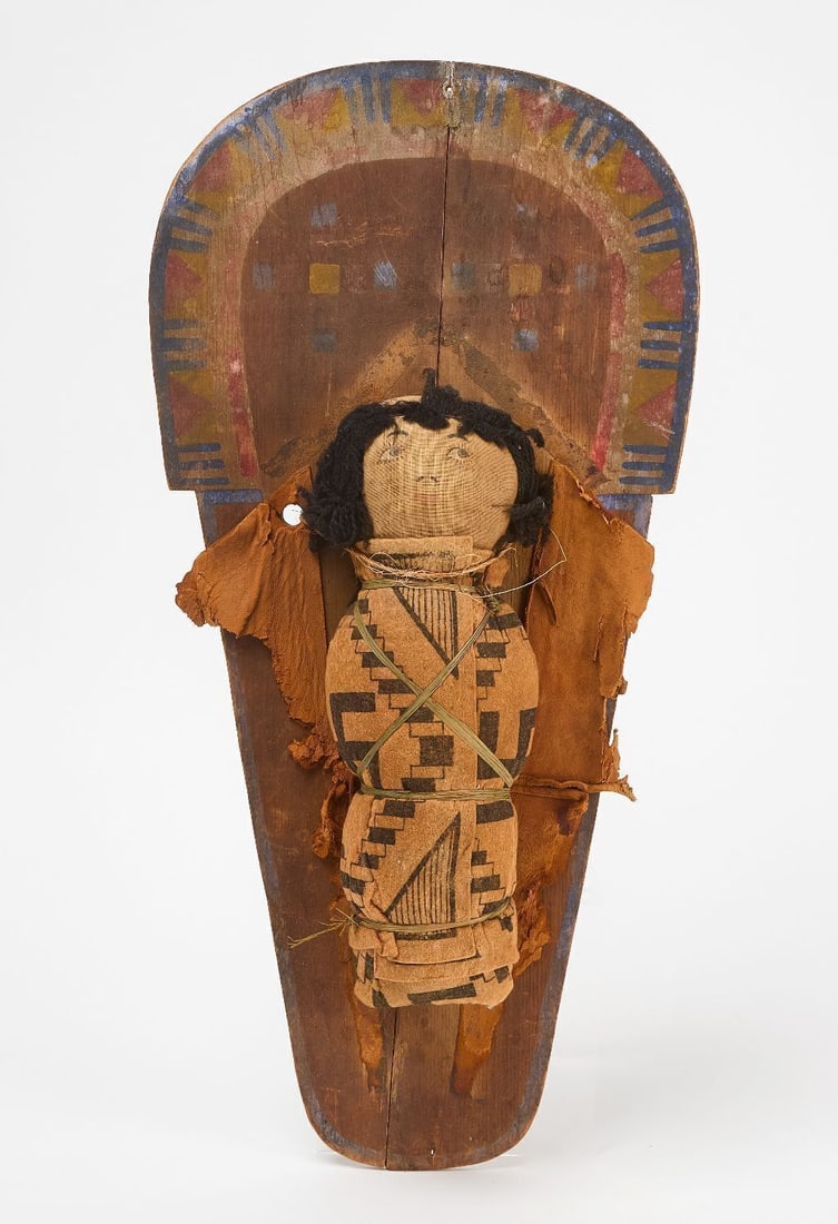 Doll Cradleboard: Doll cradleboard. Complete with doll. Original painted wood backboard. Circa 1910. H 20 in. W 9-1/2 in.