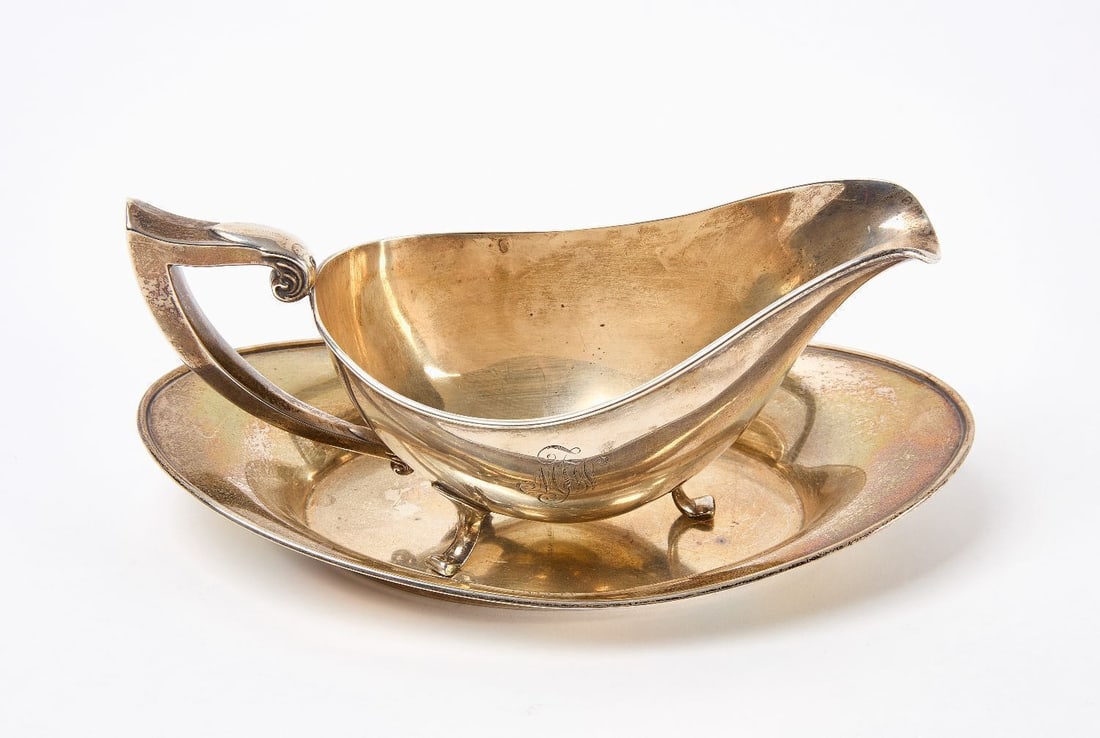 Jennings Silver Co. Sterling Gravy Boat and Dish: Jennings Silver Company sterling silver gravy boat and matching dish. Boat with scrolled handle on three flared feet. 20th century. Total Weight: 9.23 ozt. H 3-3/4 in. Dish: L 8-1/2 in. W 5 in.