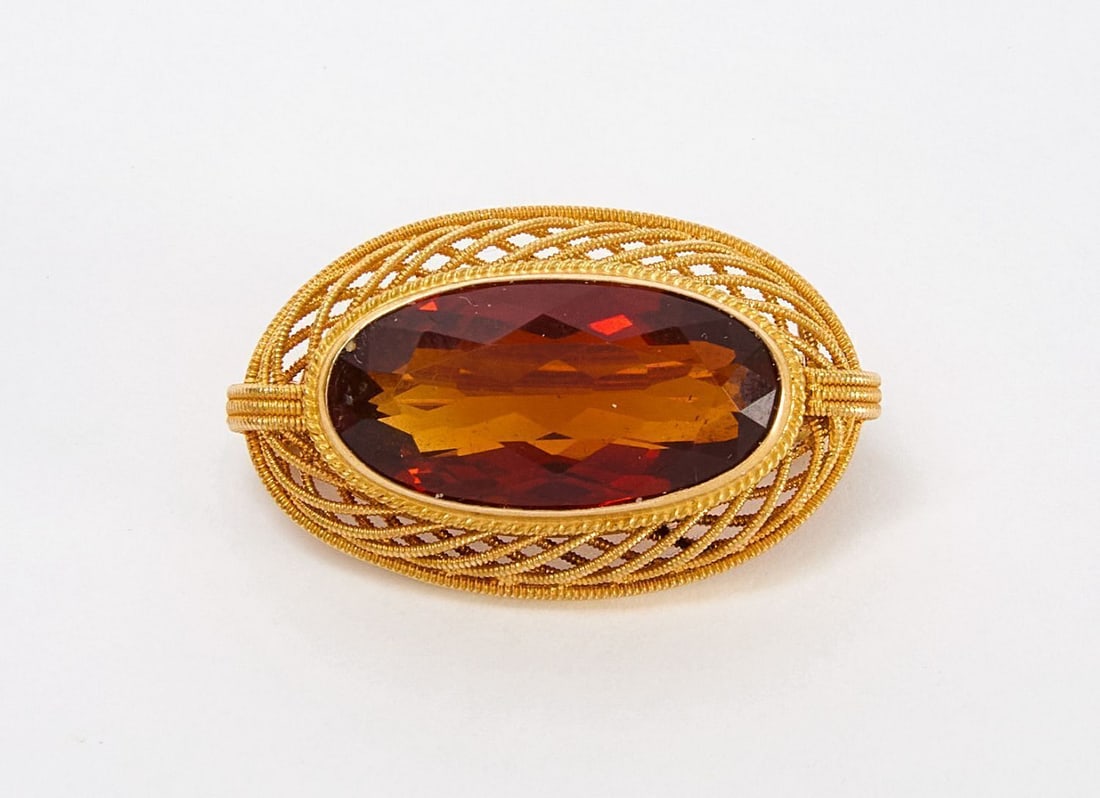 14K Gold and Citrine Pin: Lady's 14 karat yellow gold and faceted citrine pin. Stamped. Textured twisted rope setting encases stone. Pinback stem. L: 1 in. W: 5/8 in. Weight including stone: 2.9 dwt Former appraisal 