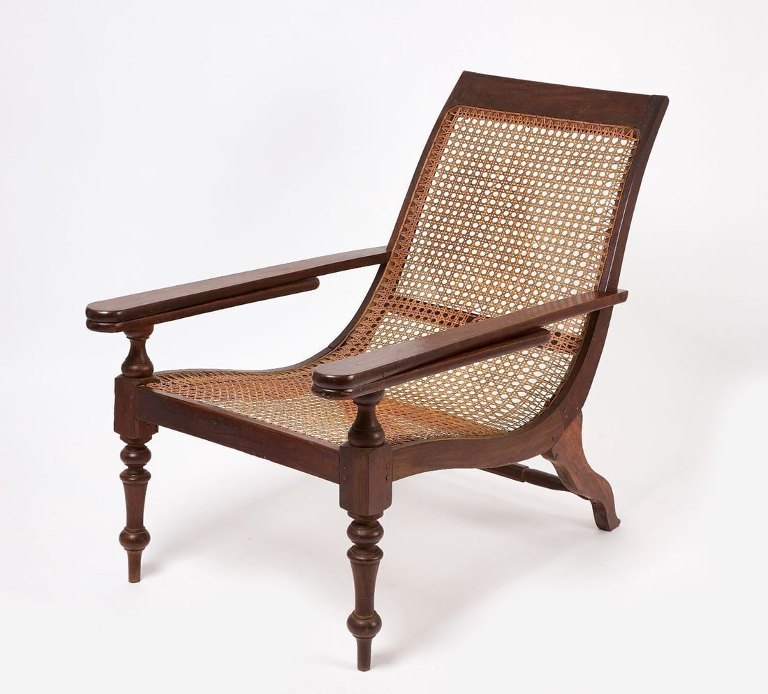 H. Don Carolis & Sons Plantation Chair: Plantation chair. Engraved bone tag for H. Don Carolis & Sons, Colombo, Sri Lanka. Cane seating with leg rests that rotate outward from the armrests. Late 19th century. H 35-1/2 in. W 25-1/2 in.