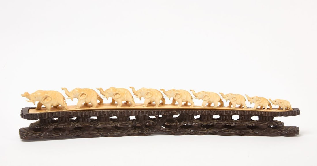 Chinese Carved Bone Parade of Elephants: Figure of a parade of elephants. Carved bone on carved wood base. China, 20th century. H 3-3/4 in. L 21-1/2 in.