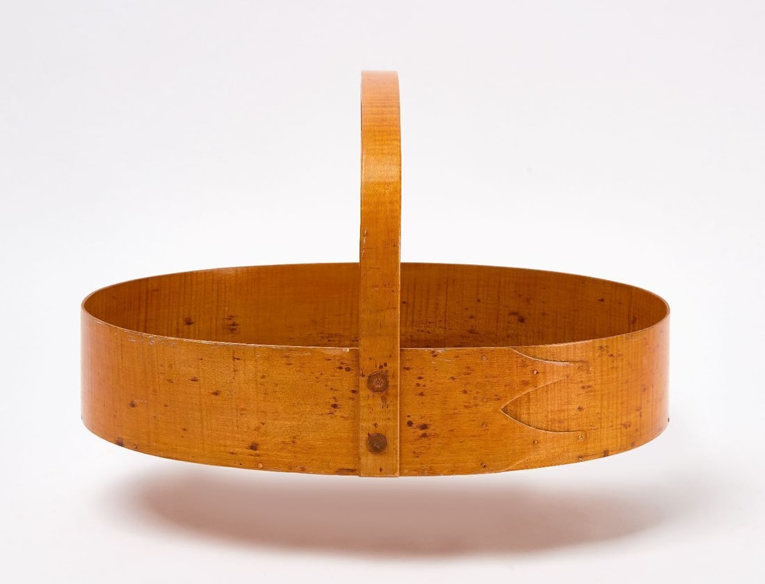 Shaker Carrier: Shaker carrier with figured maple sides and handle. New England, Circa 1900. Provenance: Estate of Faith and Edward Demming Andrews. H 9-3/8 in. W 14-1/2 in. D 10-7/8 in. Faith and Edward Deming Andre