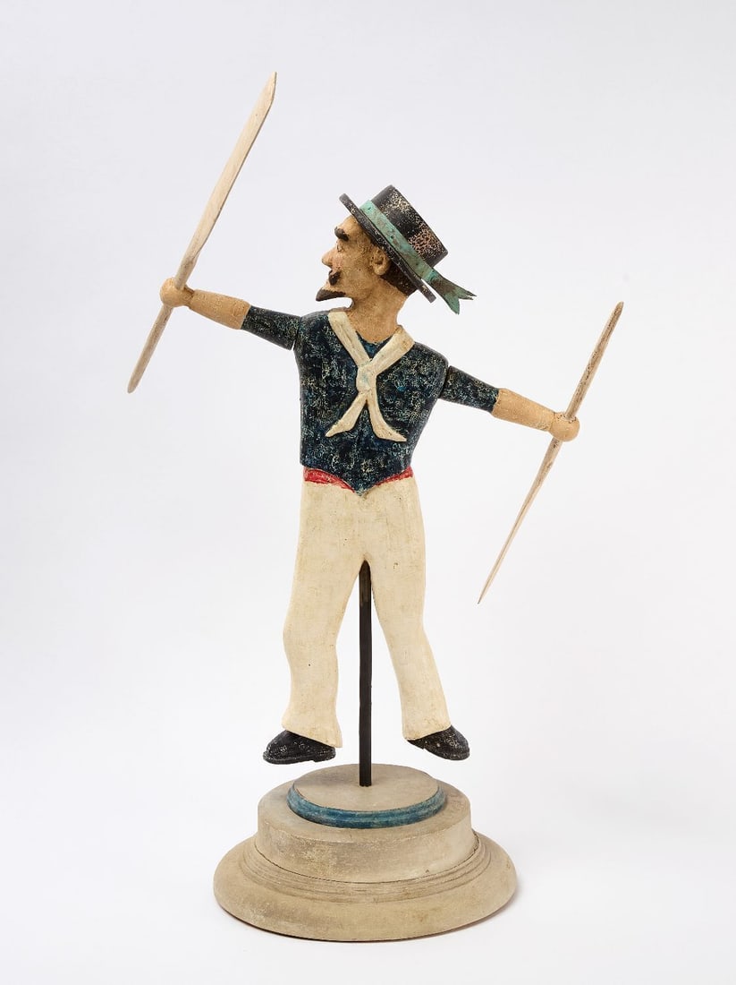 Frank Finney Sailor Whirligig: Frank Finney ( American, b. 1947), Sailor whirligig. Carved and painted wood with original stand. Applied metal ribbon around hat. Paddles resemble two oars. H (to figure) 30 in. H (paddle up) 35-1/2 
