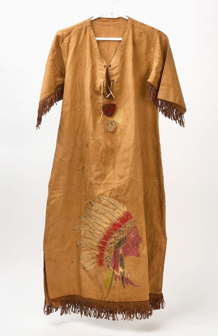 Native American Dress: Native American fringed dress with side profile painted portrait of a Native American in headdress. 20th century. L 45 in. W 36 in. 