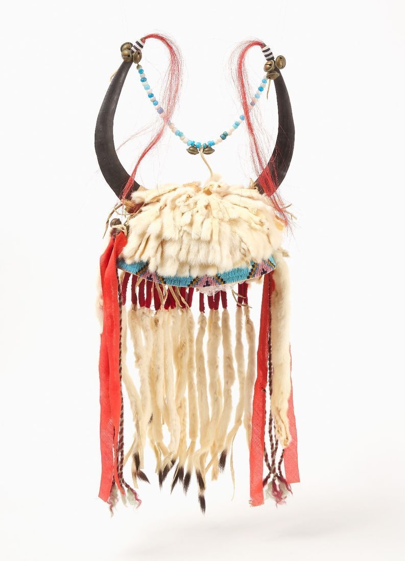 Native American Blackfoot War Bonnet: Blackfoot buffalo horn war bonnet with fur, beads, and red adornaments. Early 20th century. H 12 in. D 7-1/2 in.