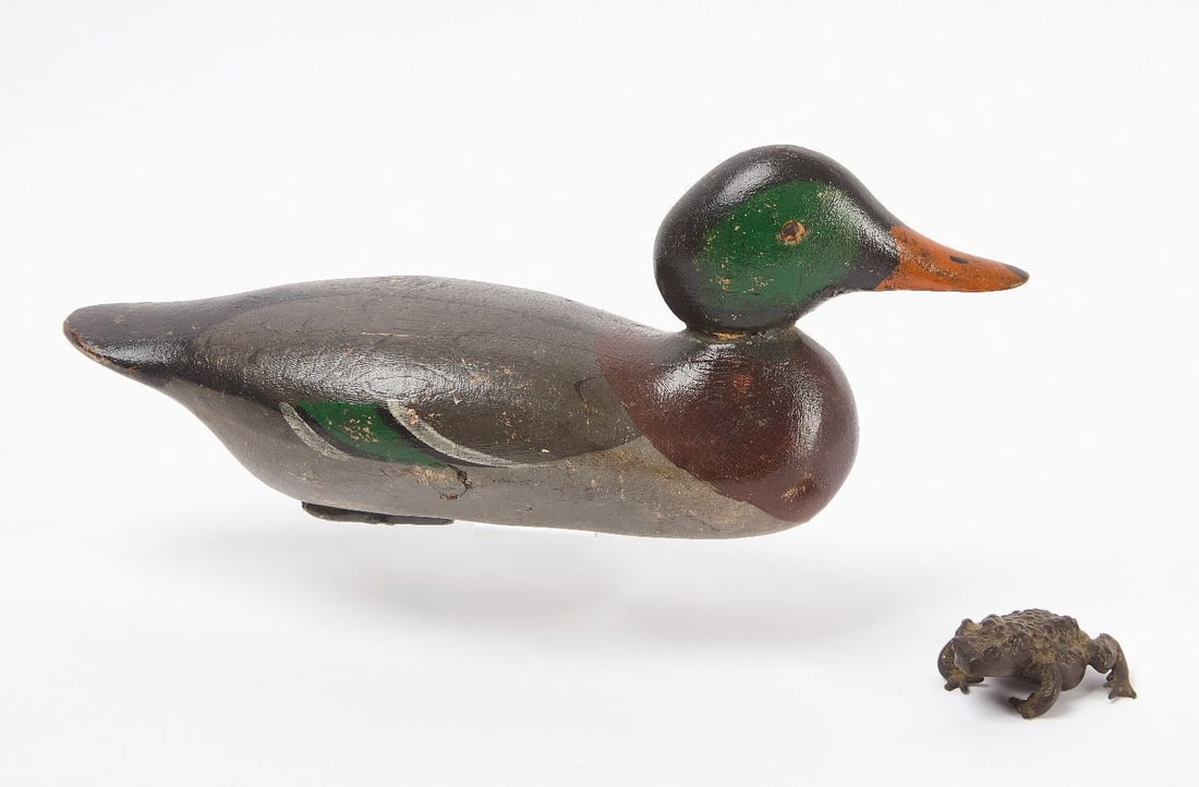 Duck Decoy and Bronze Toad: One duck decoy together with a small bronze toad. Carved and painted wood, carved eyes. Both not marked or signed. American, early 20th century. Decoy: H 6 in. L 15-3/4 in. W 5-1/4 in. Toad: L