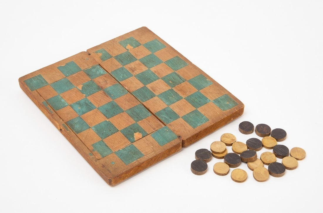 Unusual Traveling Checkerboard: Unusual folding traveling checkerboard with snipe hinges. Includes 12 white pieces and 10 black pieces. American, 19th century. Closed: H 1-3/8 in. L 8-3/4 in. W 4 in. Open: H 0-5/8 in. L 8-3/4 in. W