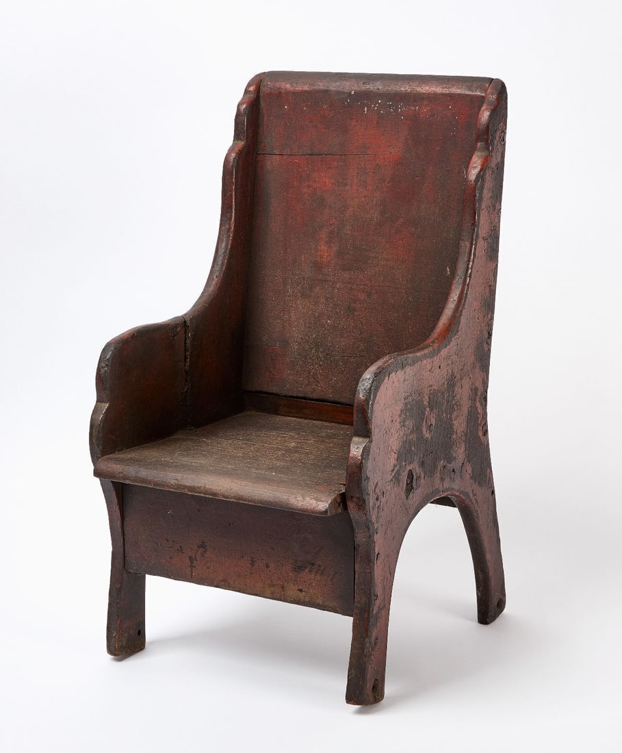 Early Painted Settle Child's Seat: Early child's settle chair with vestiges of original red paint. Pine with forged nail construction. American, circa 1800. H 22 in. W 12 in. D 12-1/4 in. SH 8-5/8 in.
