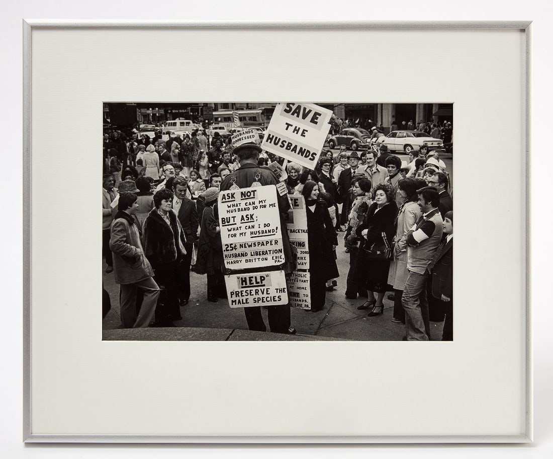 John Lester Raye - 'Save The Husbands': John Lester Raye (Connecticut, b. 1952), 'Save The Husbands'. Photograph depicting a man picketing with hand-made signs, with a crowd of onlookers (likely New York due to inscription on the ba