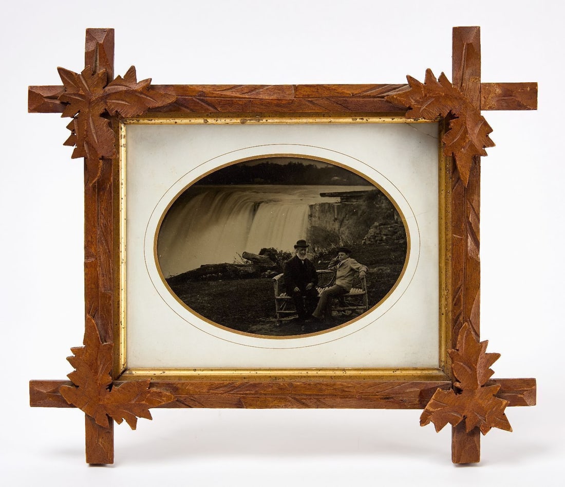 Whole Plate Ambrotype of Niagara Falls: Whole plate glass ambrotype of Niagara Falls. Shows an older gentleman and a young boy seated in a bench with the falls in the background. Period paper mat. In adirondack style wood frame with