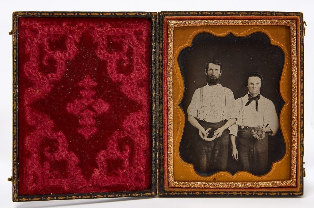 Occupational Ambrotype of Two Farriers: Quarter plate occupational clear glass ambrotype of two farriers in workwear displaying horshoes. Housed in a full leatherette case. American, circa 1870. Case: H 4-3/4 in. W 3-3/4 in. 
