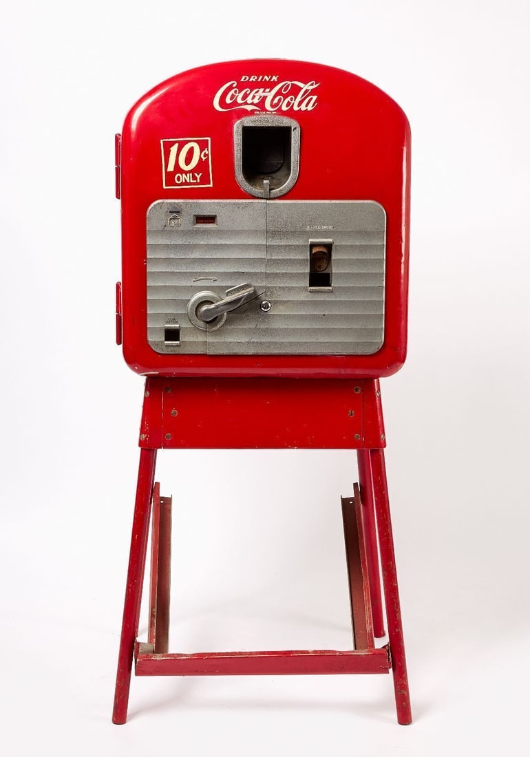 Coca Cola Vendorlator 27 Vending Machine: Coca-Cola Vendorlator-27 vending machine on original stand. 10-cent operated. American, circa 1940. (On Stand) H 57-1/4 in. W 24-1/2 in. D 22-1/2 in. Provenance: Collection of Paul and Dodi Algiers