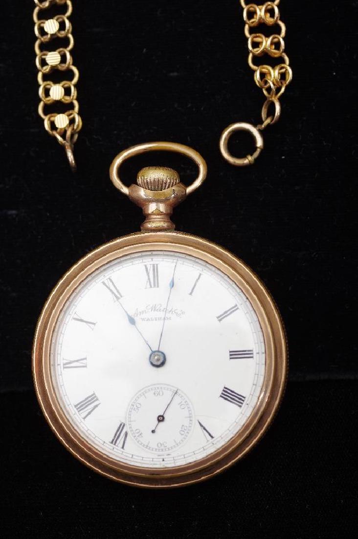 Waltham American Watch Company Gold Filled Pocket Watch: Open case, white enamel dial with Roman numerals in black, with seconds hand, engraved shield obverse, with watch chain in low content gold. Watch 55 mm.D., chain 20.75 in.L. Condition: Areas of