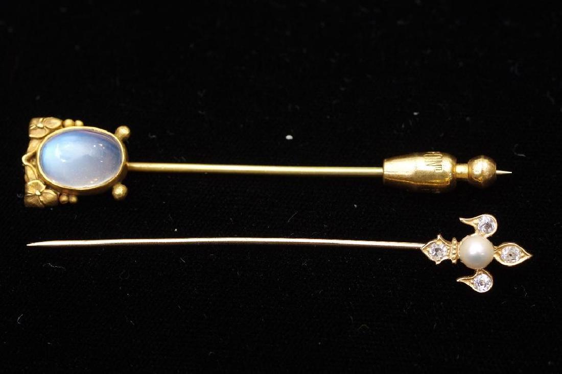 Two Antique Gold Diamond, Pearl and Moonstone Stick: Gold, diamond and pearl fleur de lis with four diamonds of approximately 1/16 ct. wt. The pearl 4.5 mm , 5/8 in.H. of fleur de lis, together with a cabochon moonstone in gold art nouveau setting,