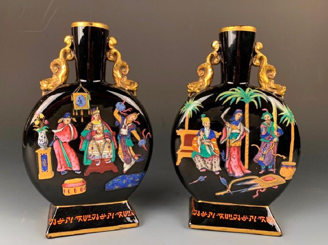Pair of English Chinoiserie Enameled Glass Moon Flasks: 19thc, each in opaque black glass, of spherical form with cylindrical necks and applied gilded dolphin form handles, colorfully enameled on both sides with figures entertaining an empress. 8.5 in. h.&