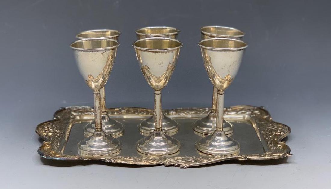 Six Sterling Silver Cordials and Tray: Repousse decorated tray with simple form weighted cordials. 9.5 x 6 in, tray, 4.56 oz. troy, tray . Condition: A few small dents to cordials, normal wear to both tray and cordials