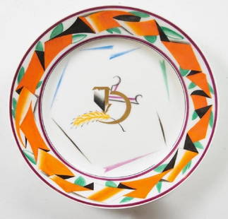 A Soviet Propaganda Porcelain Plate, 1919: State Porcelain Factory, Petrograd, after a design by Sergei Chekhonin, decorated with a hammer and sickle in partial gilt, with a sheaf of wheat, the border decorated with a stylized ribbon form in o