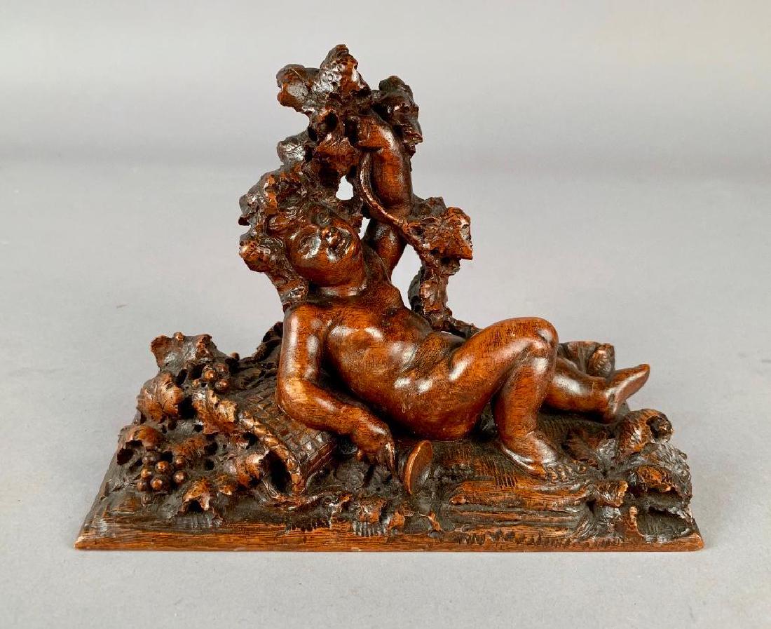 Italian Carved Wood Figure Signed A.Cheloni: 19thc, carved in the form of a drunken putto reclining on a basket of grapes, holding a spilled cup, signed A.Cheloni Firenze. 5.5 x 7.5 x 3.5 in. Condition: Old loss to one toe of putto.&nb