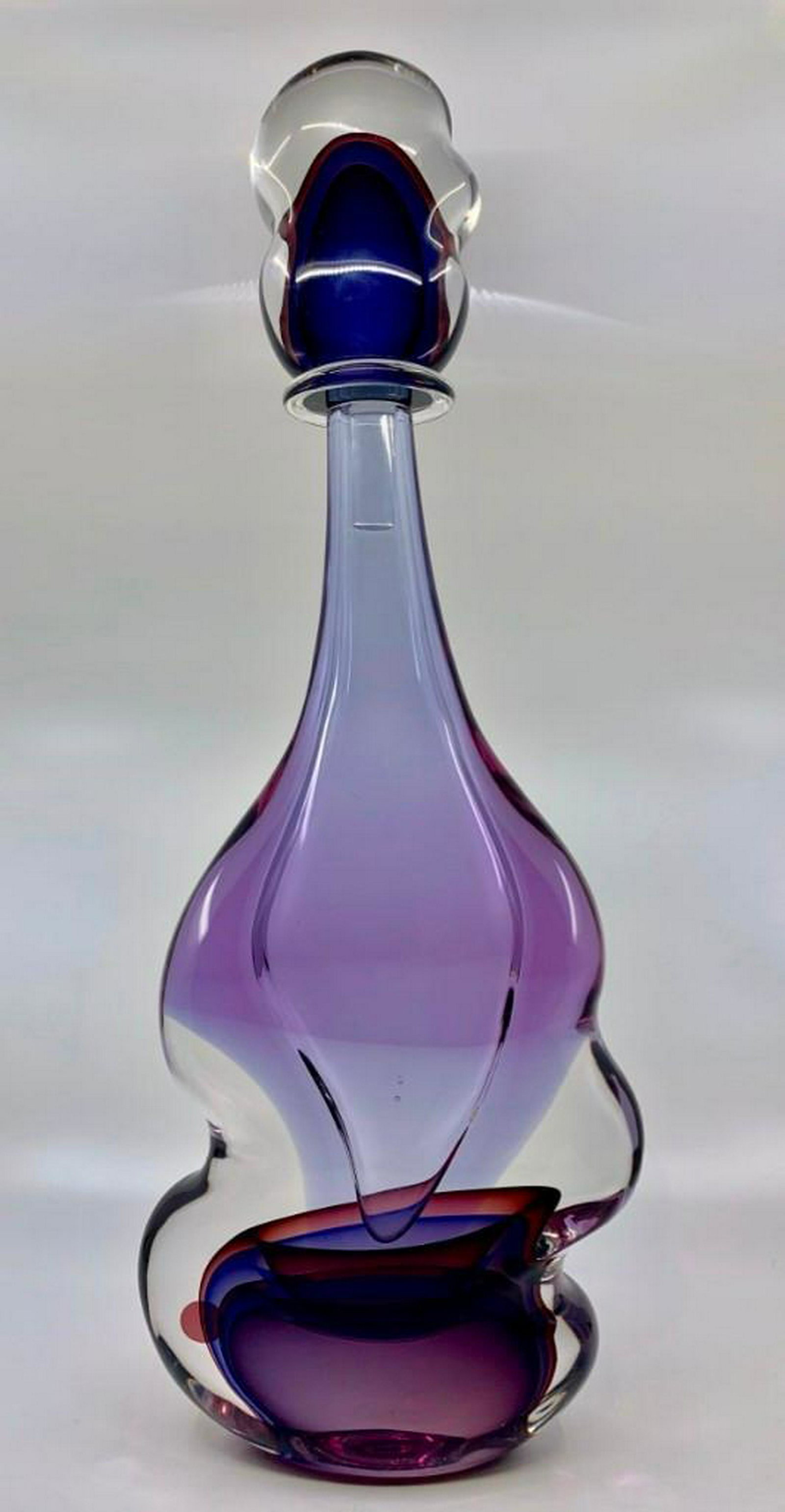 Large Luigi Mellara Art Glass Stoppered Bottle: Luigi Mellara (Italian, 20thc.). Undulating form in clear glass internally decorated with overlapping purple, with large similarly formed stopper. Signed L. Mellara with incised signature. 22 in. h. C
