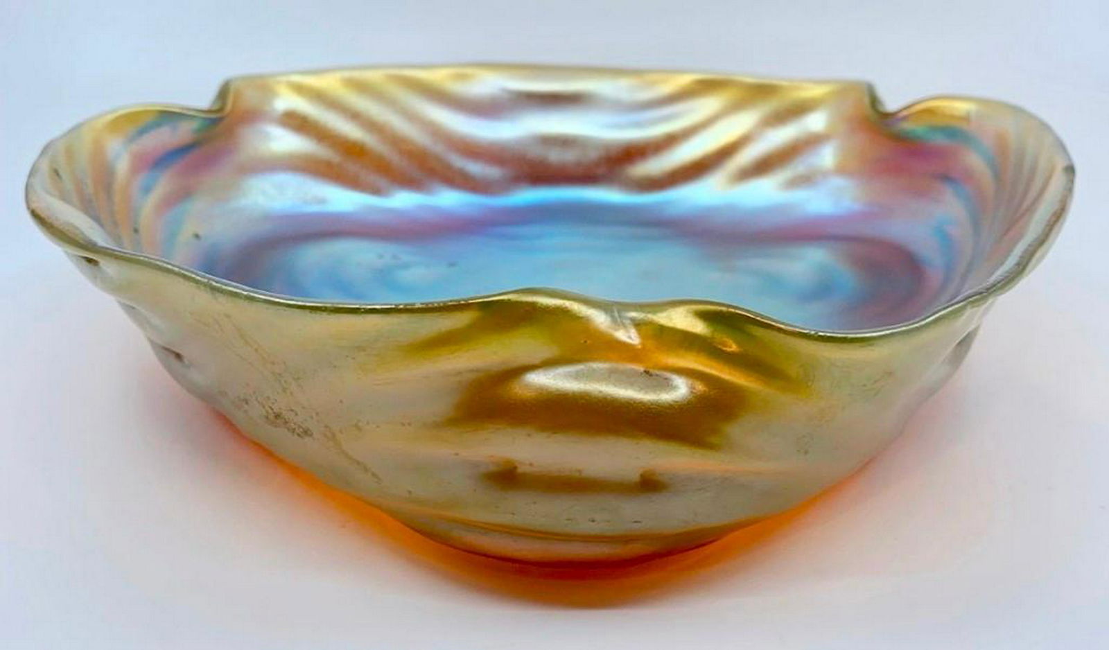 Loetz Iridescent Glass Vide Poche: Triangular rippled form with pinched corners in iridescent bright gold glass shading to blue and green. 9.7r 5 in. dia. Condition: Some bubbles in the making,some wear to finish on dish interior, othe
