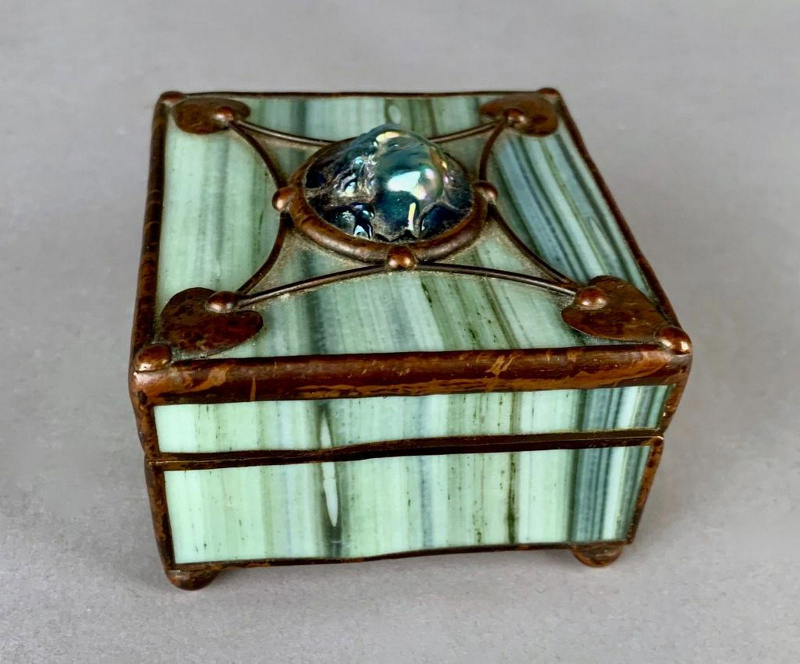 Orient and Flume Art Glass Box: Orient and Flume Art Glass BoxIn Art Nouveau style, the squared form in striated green glass with copper leaded construction, the hinged top centered by an iridescent glass cabochon molded with the fa