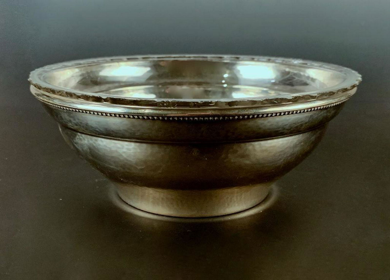 Georg Jensen Silver Bowl: Tapering hand hammered bowl with finely beaded rim, fitted with clear glass insert. 6.46 oz. troy 6.5 in. dia. 2.5 in. h. Condition: One small dent to side of bowl, glass insert with chips to rim.