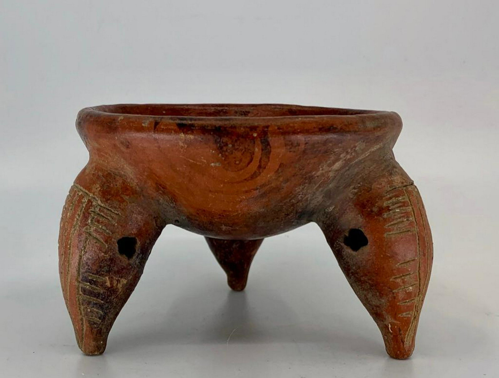 Pre Colombian Tripod Vessel: Bowl form raised on bulbous tripod legs, the interior and exterior of bowl painted with a geometric pattern, with incised designs to the legs. 3 in.h x 4in.dia. Condition: Good condition with normal w