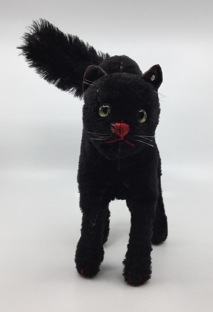 Steiff Black Cat: Steiff black cat in mohair, with black velvet ears, with back and tail up in alerted position, button in ear. 12.5 in. h. to top of tail. Condition: wear to mohair and velvet. Tail bent close to body