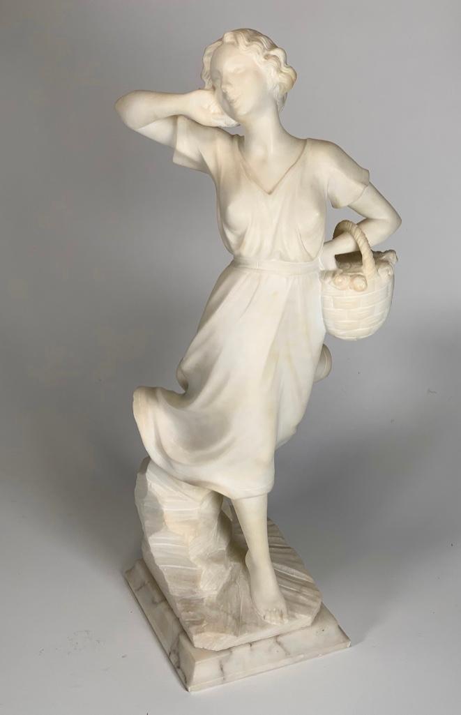 Carved Alabaster Figure of a Young Woman: Carved Alabaster Figure of a Young Woman, a 1920's era girl in a wind blown dress carrying a basket of flowers. 18.5 in.h. Condition: Very good with some minor chips.