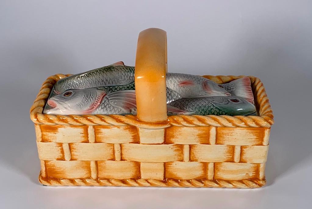 A Sarreguemines Majolica Fish Basket Tureen: A Sarreguemines Majolica Fish Basket Tureen, of rectangular woven basket form with handle, the cover modeled as a pile of fish with a fish tail serving as handle, impressed Sarreguemines with initials