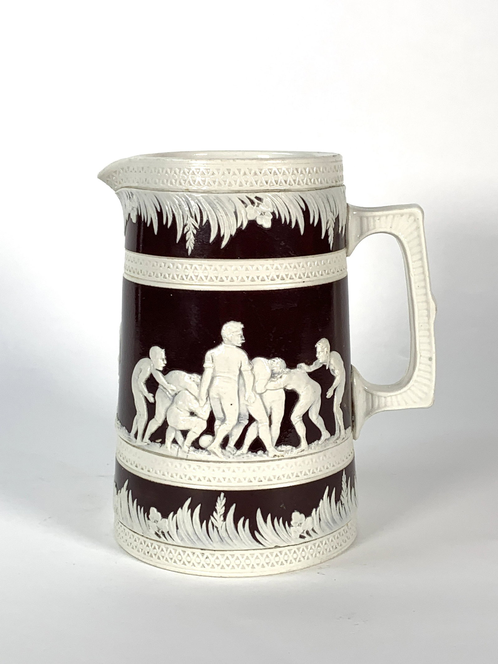 Copeland Late Spode Football Jug: Tapering form in brown glaze with jasper relief decoration of a football scrum and a kicker kicking to a goal post, impressed England Copeland, 19, Football, with brown transfer print mark, and regist