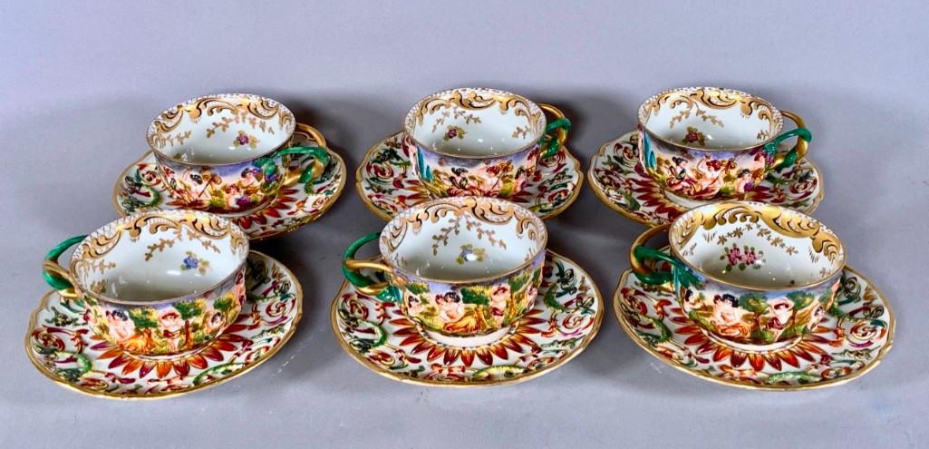Six Capodimonte Cups and Saucers: Six Capodimonte Cups and Saucers, molded in relief and hand painted with scenes of a 'Fete Champetre,' with hand painted scroll, floral and gilded embellishments. Crowned N mark in underglaze blue. Di