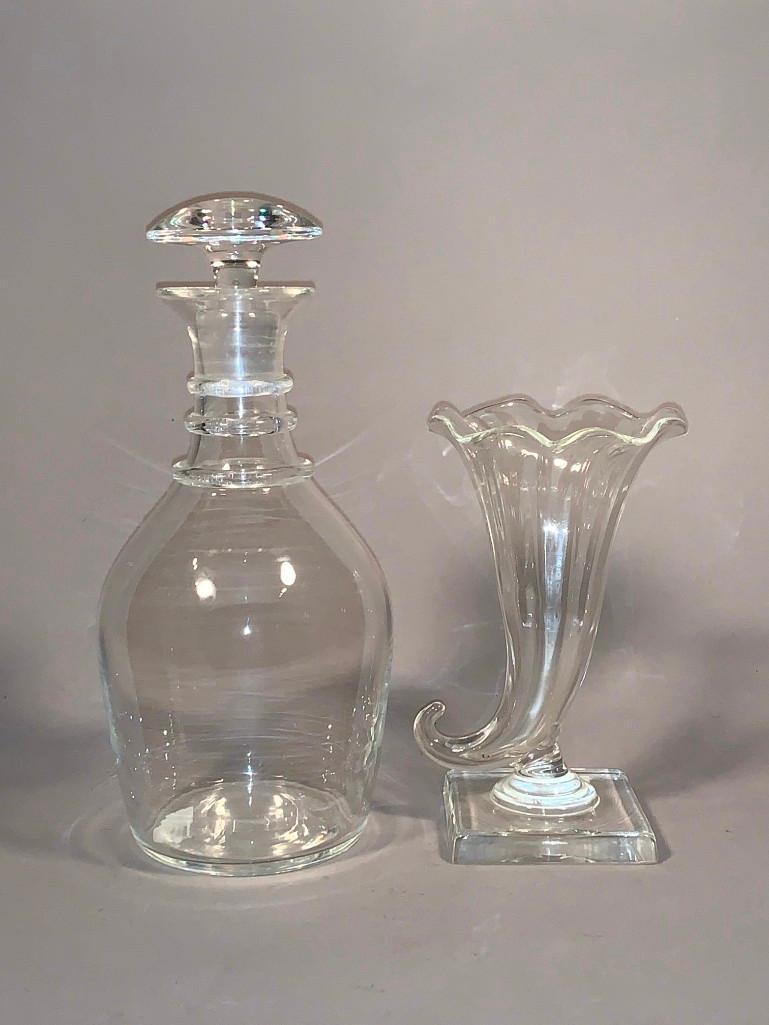A Steuben Crystal Decanter and a Cornucopia Vase: A Steuben Crystal Decanter and a Cornucopia Vase, baluster form decanter with three rings at neck and flat domed stopper, cornucopia vase on squared base. Dimensions: 10 in.h. Decanter, 6.75 in.h. vas
