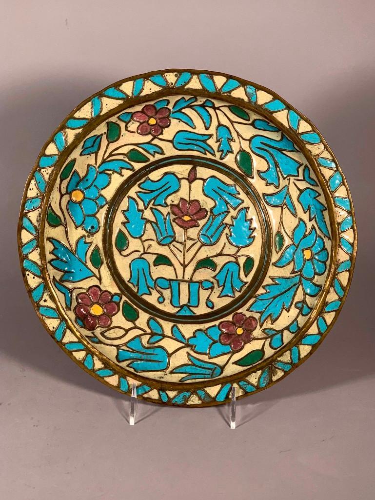 Antique Syrian Enameled Copper Plate: Antique Syrian Enameled Copper Plate, enameled with a floral pattern in turquoise, cream, green and plum colors. Dimensions: 12.5 in. dia. Condition: Good with some crazing and losses.