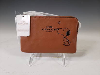 Coach Snoopy Peanuts Corner Zip Wristlet, Saddle NWT: Coach® Peanuts Snoopy Corner Zip Wristlet, Saddle Dark Tan Leather. Saddle Leather and Palladium Hardware. Model Number: F65193. Suggested Retail $95.00 Dimensions: 4.25 x 6.25 in. Condition: New and