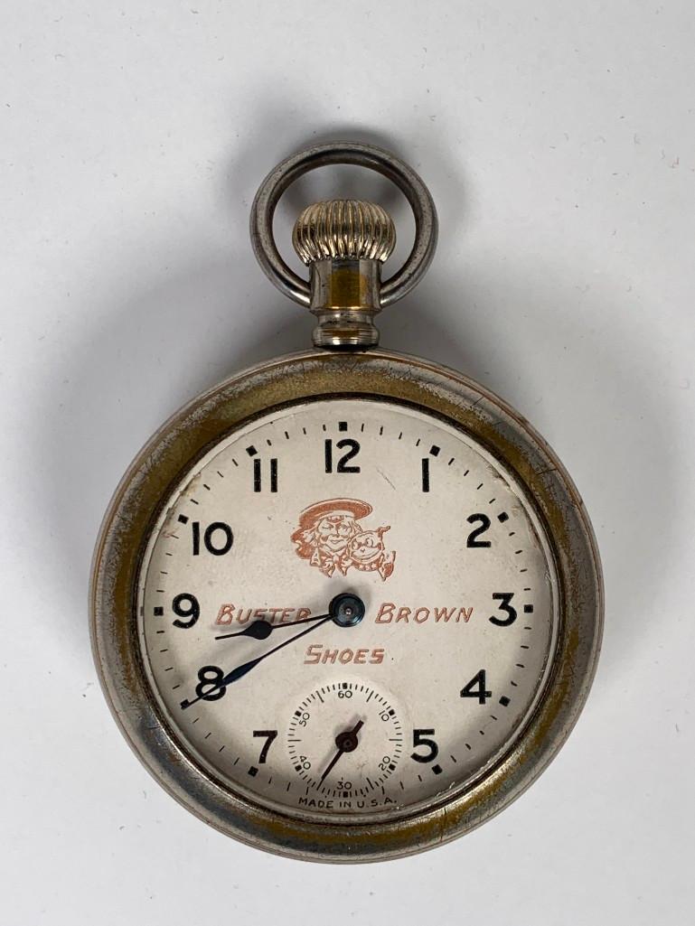 Buster Brown Character Pocket Watch, 1929: Produced by Ansonia, white enamel dial with Arabic numerals and seconds dials, with printed logo and text advertising Buster Brown Shoes. Includes original box with paperwork. 2"D case, 2.25" square b