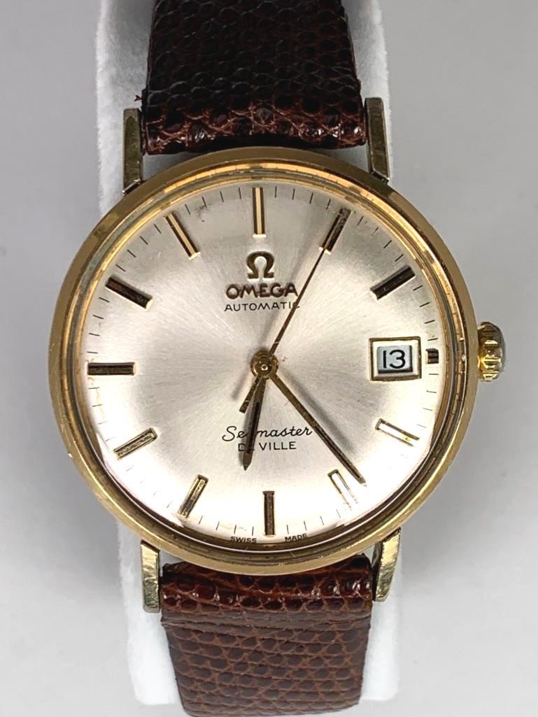 Vintage Omega Automatic Seamaster Deville Wrist Watch: Swiss made, matte silver tone dial with date, gold toned hour markers, the back of case engraved and dated 1975, Flat profile, the glass with a few tiny scuffs, on a brown lizard strap with gold tone