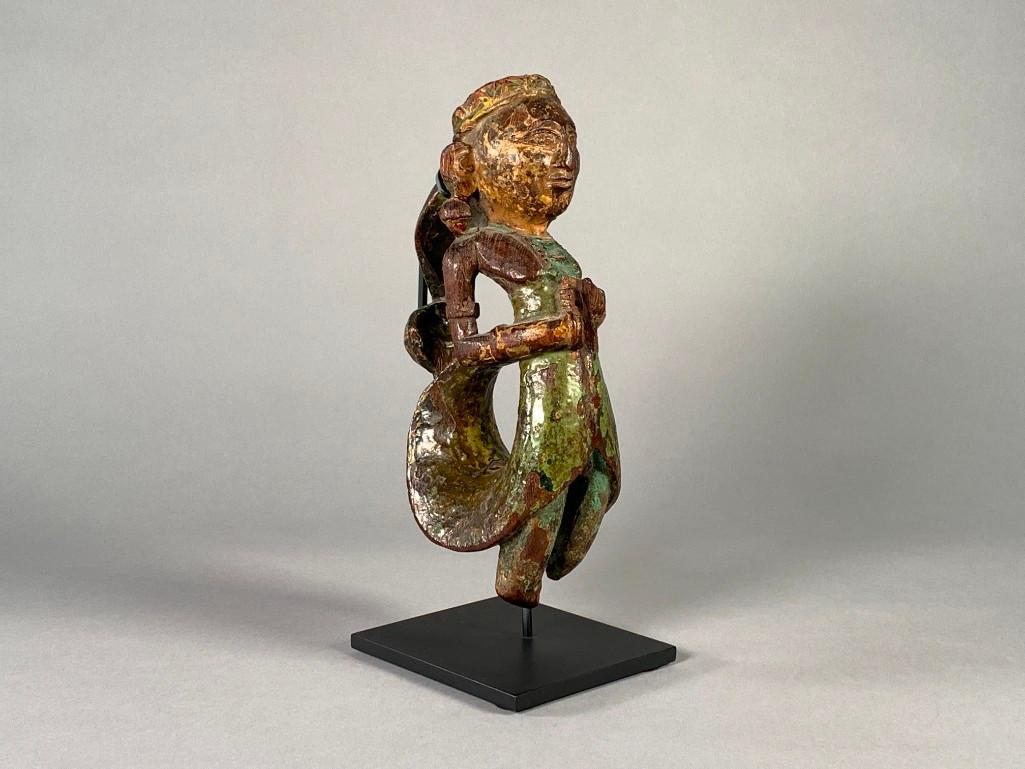 Southeast Asian or Burmese Carved Wood Ornament: Southeast Asian or Burmese Carved Wood Ornament, carved and polychromed figure with arched back and curled coat tails, wearing small hat and with large ear ornaments. On custom made fitted metal stand