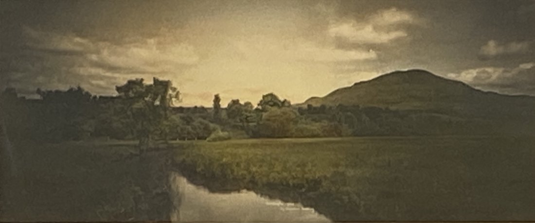 Wallace Nutting, "Across The Meadows": Wallace Nutting (American 1861-1941) "Across The Meadows", hand-colored photograph, signed in ink lower right, framed. Dimensions: 4 x 9.5 in. image size, 10.75 x 16.75 in. as framed. Condition: As is