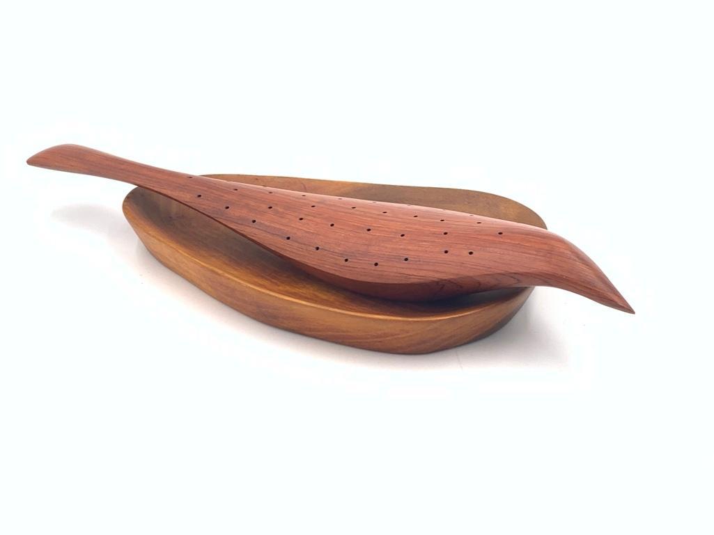 Emil Milan Carved Wood Bird: Emil Milan (American 1922-1985) Two Carved Wood Items, including a bird or fish shaped form with holes, signed Emilan, Bubinga; and an ovoid shaped dish. Dimensions: 15 in.l. and 10 x 6 in. Conditio