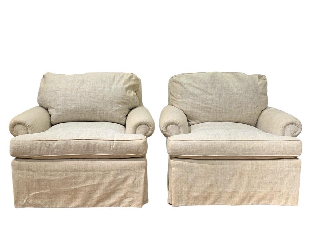 Pair of Linen Upholstered Lounge Chairs: Pair of Linen Upholstered Lounge Chairs, Scroll arms and loose cushion backs with box pleated skirts in cream linen. Dimensions: 30 in.h. x 37 in.w. x 35 in. d. Condition: Upholstery with some stainin