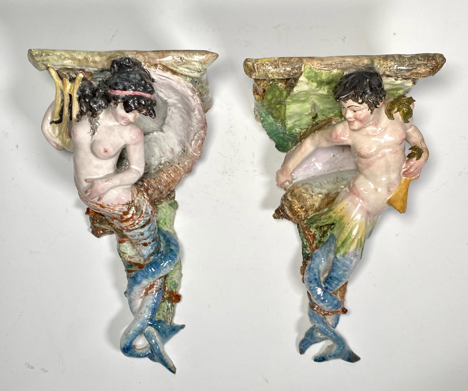 Pair of Italian Tin Glazed Majolica Mermaid and Merman Wall Brackets: Pair of Italian Tin Glazed Majolica Mermaid and Merman Wall Brackets, late 19thc, modeled as a Mermaid with a lyre and a Merman with a large conch shell supporting a bracket top, glazed in blue, green
