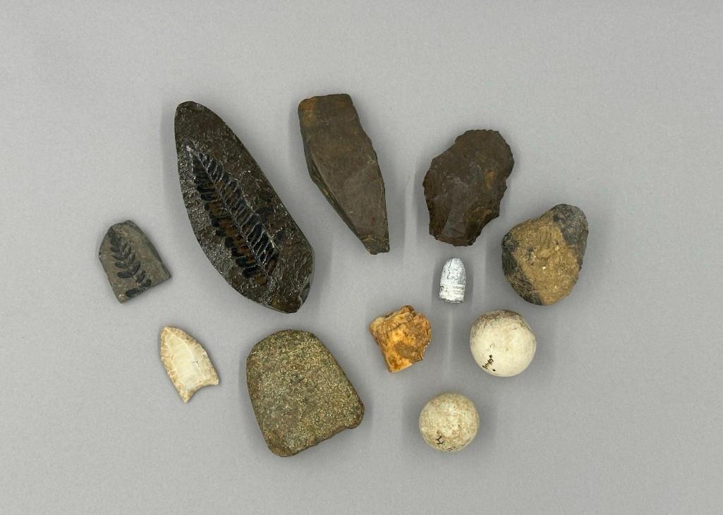 Excavated Items: Lot includes eleven found objects including a Civil War era bullet, arrow head, two round stones, a bone fragment, two fern fossils in matrix and four Native Indian tool heads.