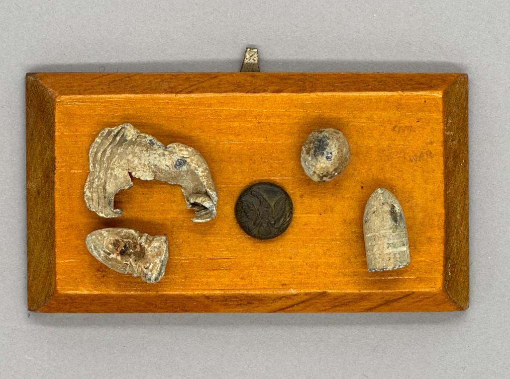 Ammunition Fragments: Small display collection includes a smashed Union bullet, round ball, 58 caliber Confederate bullet and a 58 caliber Union bullet and one button in the center. Attached to a beveled wood plank, read t