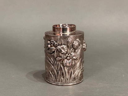 Japanese Meiji Silver Tea Caddy: Japanese Meiji Period Tea Caddy is densely decorated with high relief motifs of iris growing by a stream. They are placed against a hand tooled background. Created in Japan for the western market,