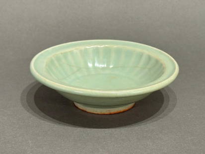 Chinese Celadon Dish: Chinese Celadon Dish, probably 18th-19th century in date, is a molded form with fluted sides. The stone ware body is evident on the foot rim. Provenance: Two inventory seals on base; Brodie & Enid Lo