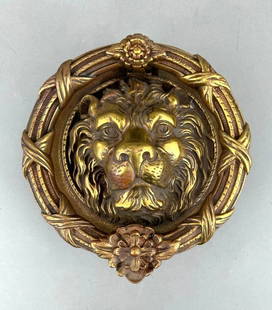 Large Bronze Lion Mask Door Knocker: Large Bronze Lion Mask Door Knocker, cast as the face of a serene looking lion centering a large ring handle with ribbon ties and floral motifs. The lion head modeled after a Roman original.  Dimensio