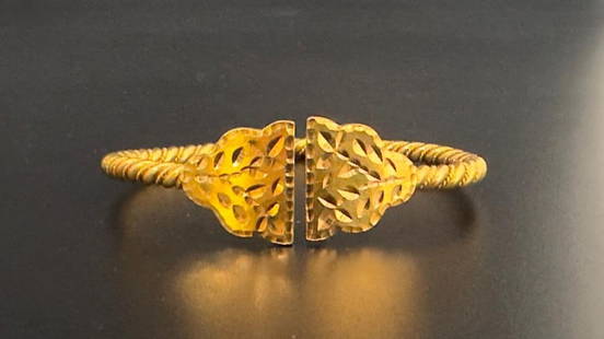 21K Gold Bangle Bracelet: 21K Gold Bangle Bracelet, Twisted rope bangle, terminating to engraved, flat triangles, stamped on verso 21K. Weighs apprx 39.64 grams, apprx 2.5"D. From the collection of Juliane and Philip Lynch, Sh